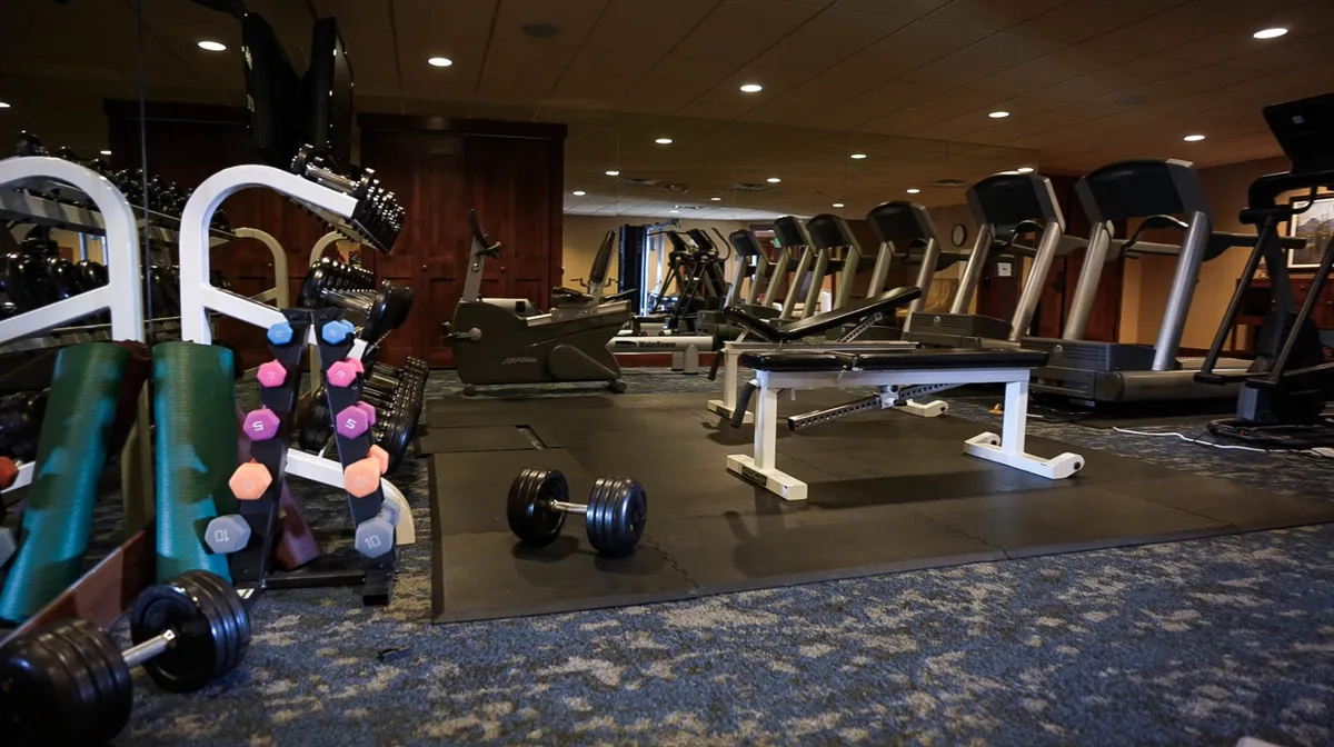 A bright, modern exercise facility featuring an array of cardio machines, free weights, and a mirrored wall. The space is inviting and well-equipped, supporting an active lifestyle for guests who want to balance adventure with fitness and wellness.