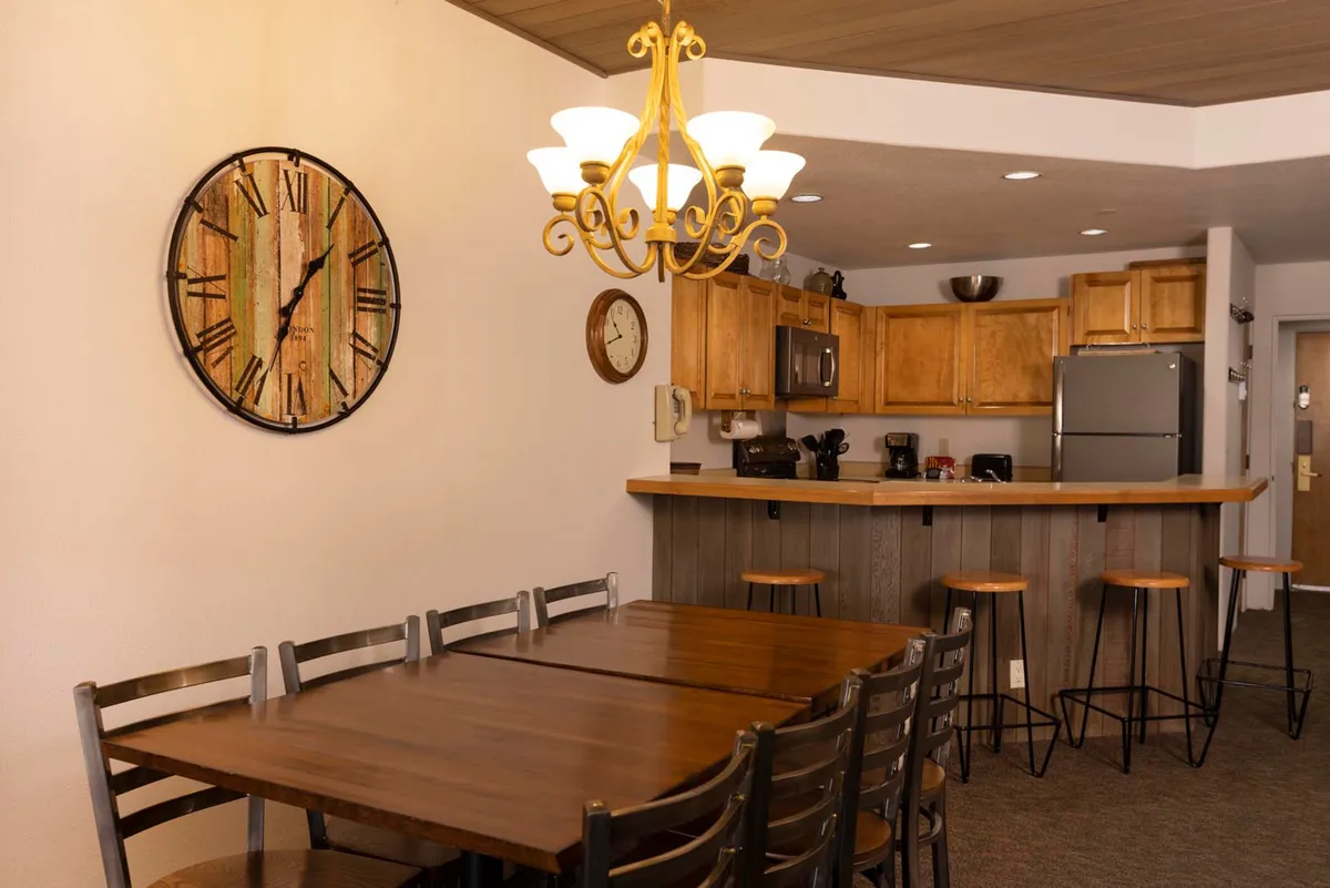 A welcoming dining area with a central dining table, eye-catching chandelier, and adjacent kitchen bar. The space is designed for family meals, friendly gatherings, and making lasting memories together in a cozy, communal setting.